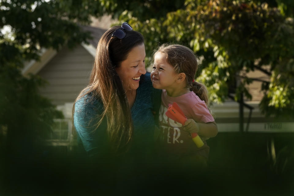 Claire Reagan plays with her daughter Abbie, 3, Monday, Sept. 21, 2020, outside her home in Olathe, Kan. Reagan is keeping her son Evan, 5, from starting kindergarten and her daughter from preschool due to concerns about the coronavirus pandemic. (AP Photo/Charlie Riedel)