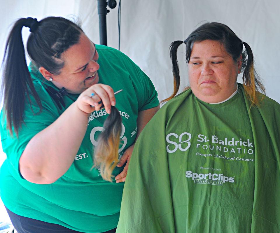 Stylist Brittany Aufrance holds up a tuft of hair from donor Mary Richard on Sunday, Sept. 18, 2022, at Buffalo Wild Wings during the 7th annual Alliance St. Baldrick's event to benefit the foundation that supports children battling cancer.