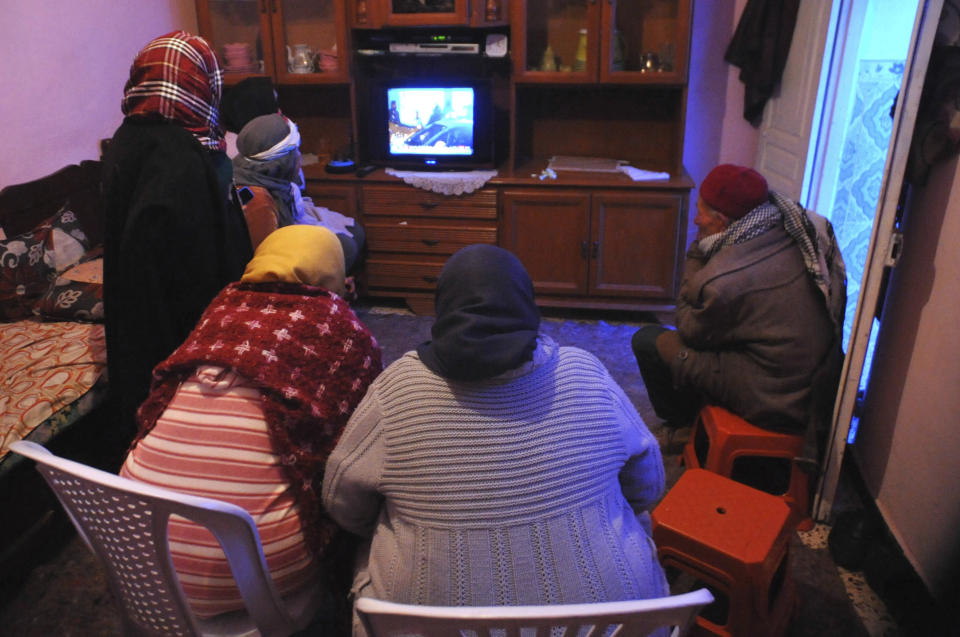 Nour El Houda Hassani, the mother of Anis Amri, second left with white headband, and his father Mustapha Amri, right, watch television with others after the death of their son, in Oueslatia, central Tunisia, Friday, Dec. 23, 2016. Anis Amri, the Tunisian-born suspect in the Berlin truck rampage that killed at least 12, was shot dead early Friday in the outskirts of Milan, Italy. (AP Photo/Anis Ben Salah)
