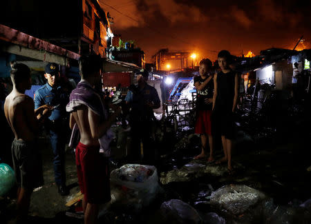 Police officers interrogate teenagers after they are rounded up lingering in the streets of Tondo, Manila, Philippines July 2, 2018. REUTERS/Erik De Castro/Files