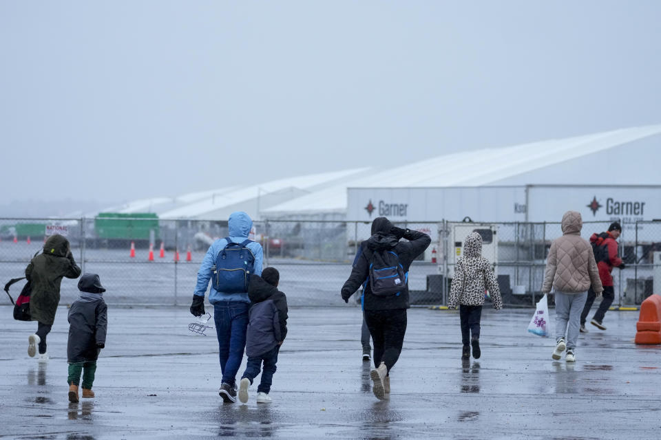 Immigrants run in the rain towards the tents at migrant housing location at Floyd Bennett Field, Tuesday, Jan. 9, 2024, in New York. New York City will evacuate the nearly 2000 immigrants housed in tents at the site due to an impending storm. (AP Photo/Mary Altaffer)