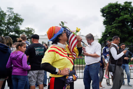 Victoria Kim, a Vietnamese Trump supporter from California, kisses an American flag during a vigil outside the White House to celebrate the joint summit between U.S. President Donald Trump and North Korean leader Kim Jong Un held in Singapore, in Washington, U.S., June 11, 2018. REUTERS/Toya Sarno Jordan