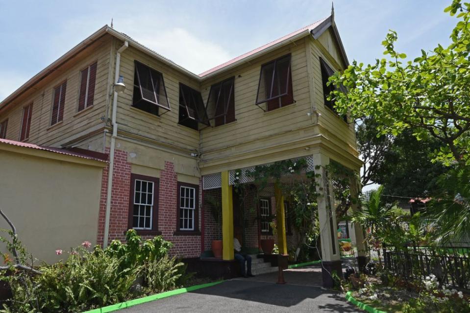 a yellow painted wooden and brick house on a sunny day