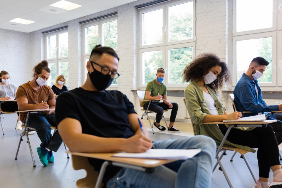 A group of students sitting at their desks in class with masks on