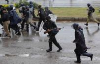 A policeman fires his weapon as he runs away with others from supporters of Tahir ul-Qadri, Sufi cleric and leader of political party Pakistan Awami Tehreek (PAT), during the Revolution March towards the prime minister's house in Islamabad September 1, 2014. REUTERS/Akhtar Soomro