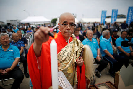 A Buddhist monk performs a ritual prayer for a good catch and safe navigation before the squid fishing ships depart from a port in Sakata, Japan, June 6, 2018. REUTERS/Issei Kato/Files