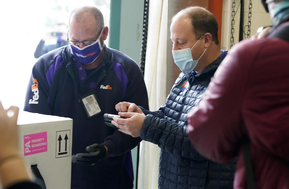 Colorado Governor Jared Polis signs for delivery of the state's first shipment of COVID-19 vaccine at the laboratory for the Colorado Department of Public Health and Environment, early Monday, Dec. 14, 2020, in Denver. (AP Photo/David Zalubowski)