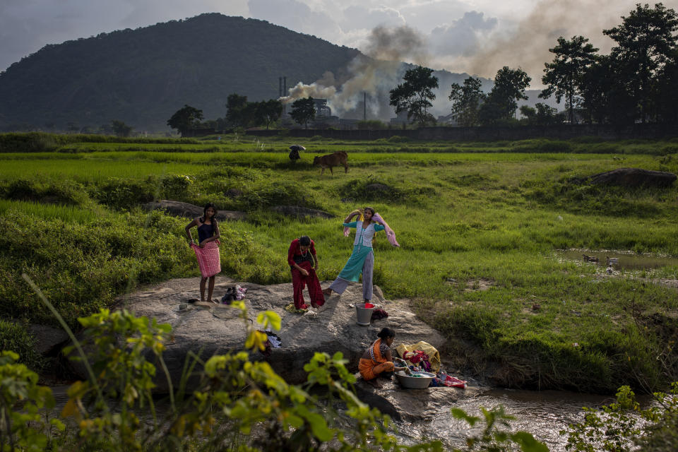 FILE - Smoke rises from a coal-powered steel plant in the background as village girls get ready after taking a bath in a stream at Hehal village near Ranchi, in eastern state of Jharkhand, Sept. 26, 2021. Loss and damage is the human side of a contentious issue that will likely dominate climate negotiations in Egypt. (AP Photo/Altaf Qadri, File)