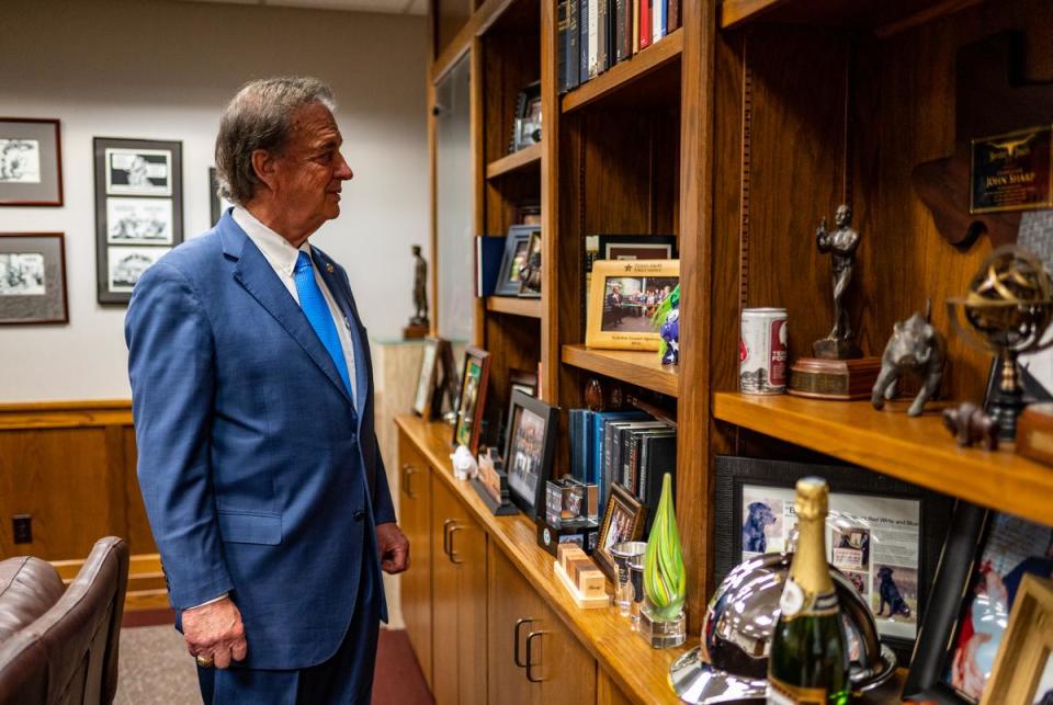 Texas A&M Chancellor John Sharp looks at a shelf with photos mementos outside his office on Monday, March 27, 2023 in College Station, TX.