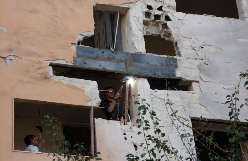Worker fixes the damage to a building from an Israeli attack in Damascus