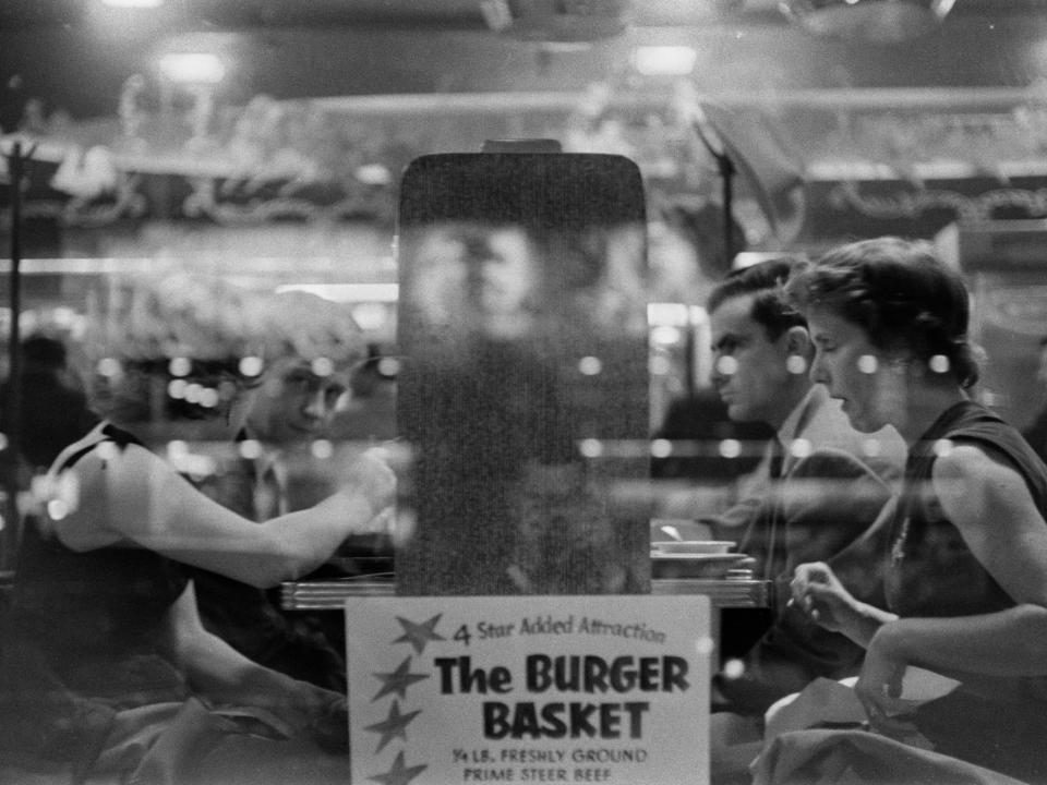 Two couples sit at a table in a diner in 1955