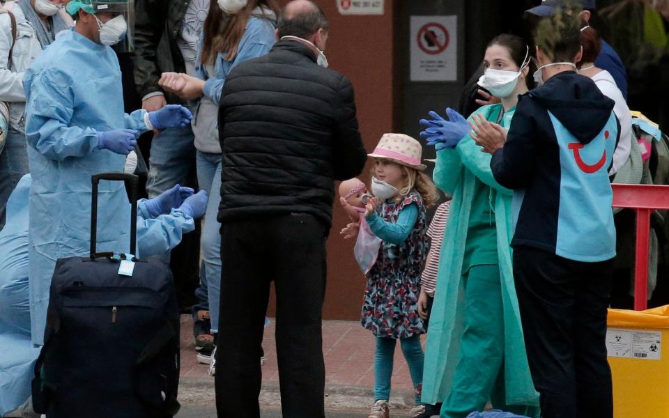 Health personnel wearing protection clothing assist guests as they leave the H10 Costa Adeje Palace hotel in La Caleta, in the Canary Island of Tenerife, Spain - Joan Mateu /  AP