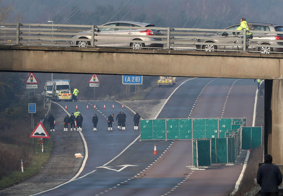 Police officers search by junction 9 on the northbound carriageway of the M20 in Kent which has been closed to traffic after a body was found on the road yesterday. (PA)