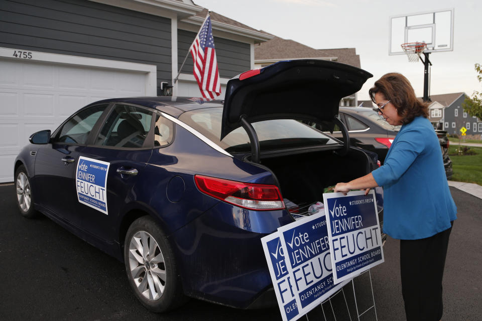 Jennifer Feucht, candidate for Olentangy Local Board of Education, delivers campaign flyers and yard signs to Brad and Tina Krider Thursday, Oct. 7, 2021, in Westerville, Ohio. Across Ohio and the nation, parental protests over social issues like mask mandates, gender-neutral bathrooms, teachings on racial history, sexuality and mental and emotional health are being leveraged into school board takeover campaigns. (AP Photo/Jay LaPrete)