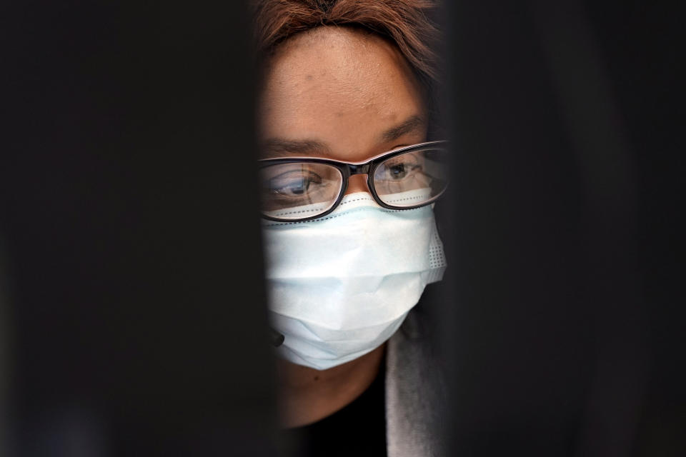 Contact tracer Astrid Zeroual is shown between two computer monitors as she works at Harris County Public Health contact tracing facility Thursday, June 25, 2020, in Houston. Texas Gov. Greg Abbott said Wednesday that the state is facing a "massive outbreak" in the coronavirus pandemic and that some new local restrictions may be needed to protect hospital space for new patients. (AP Photo/David J. Phillip)