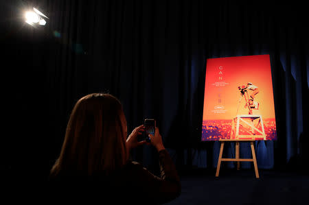 A woman takes a picture of the official poster of the 72nd Cannes International Film Festival before a news conference to announce its official selection in Paris, France, April 18, 2019. REUTERS/Gonzalo Fuentes