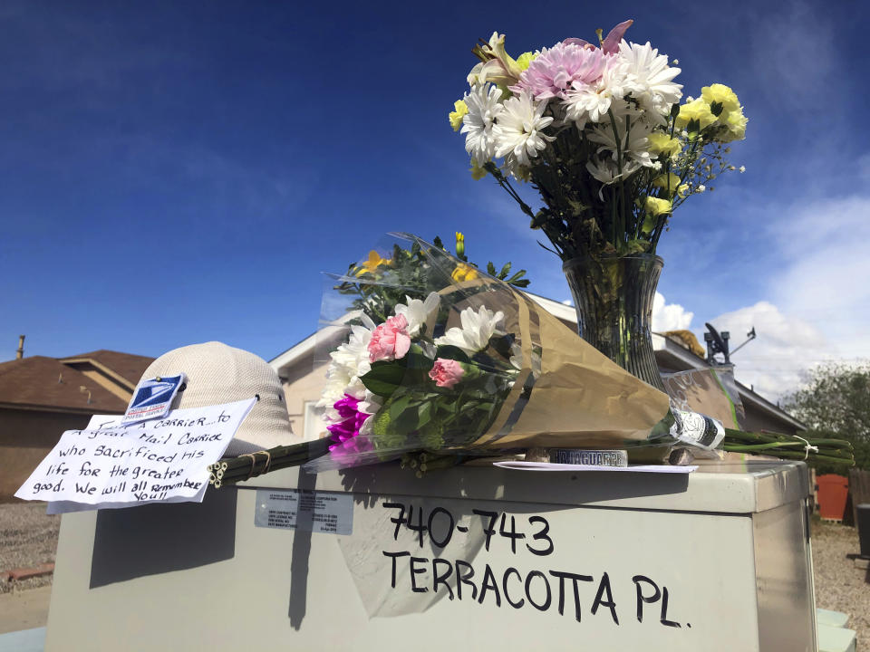 Flowers and notes are arranged atop a mailbox on Tuesday, April 23, 2019, in tribute to a mail carrier who police say was killed outside an adjacent home in Albuquerque, N.M. Police said in a criminal complaint that the mail carrier was fatally shot Monday, April 22, while trying to intervene in a dispute between a mother and her 17-year-old son, who has been identified as the shooting suspect. (AP Photo/Mary Hudetz)