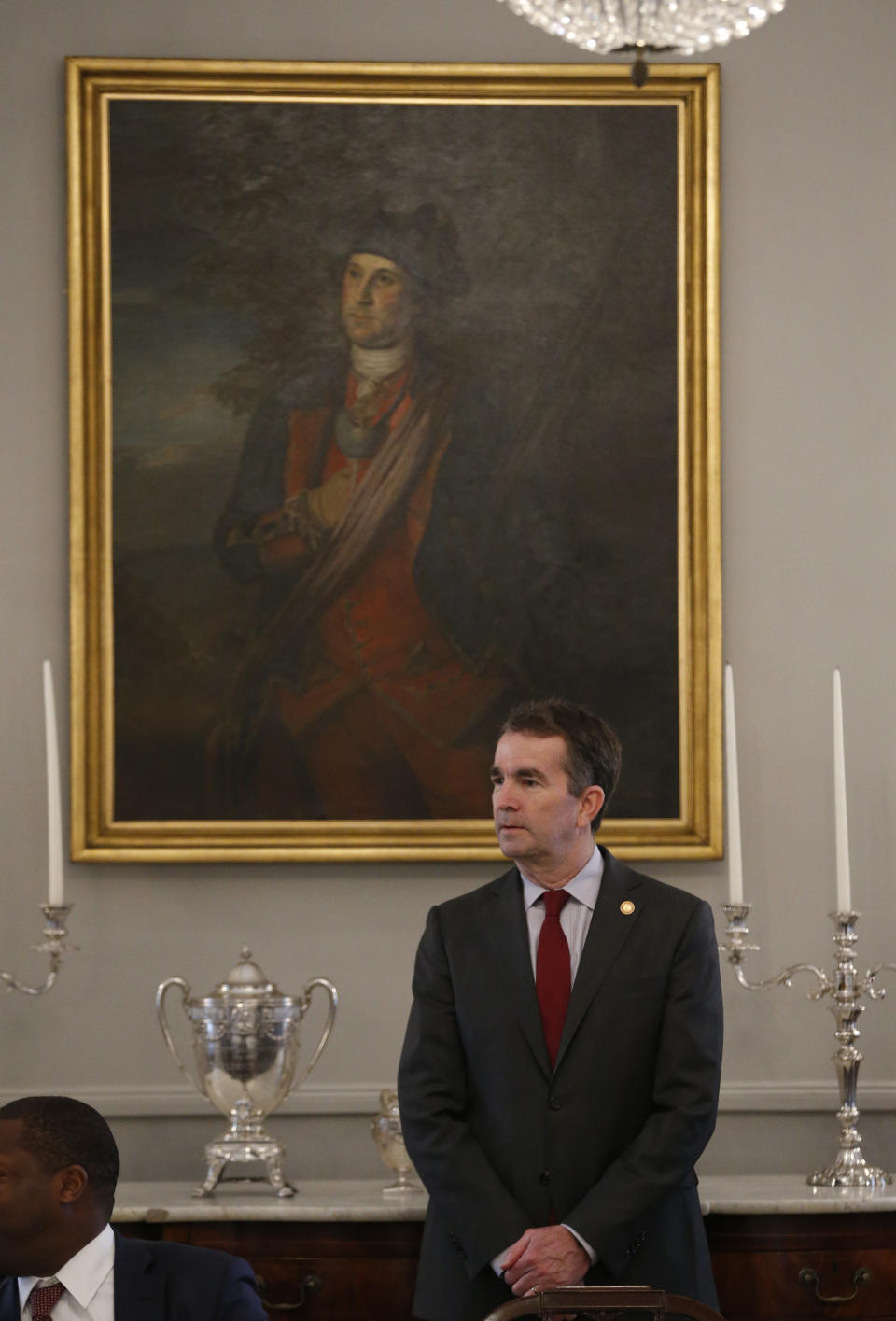 Virginia Gov. Ralph Northam stands under a portrait of George Washington as he greets members of the Richmond 34 for a breakfast at the Governors Mansion at the Capitol in Richmond, Va., Friday, Feb. 22, 2019. The Richmond 34 were a group of African Americans who defied segregation laws in the 1960's (AP Photo/Steve Helber)