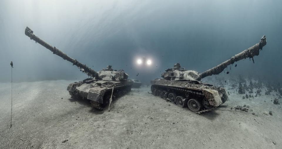 Two Chieftain tanks on the sea floor at the Aqaba underwater military museum in Jordan, with two lights behind them. The image is a winner in the 2024 Underwater Photographer of the Year Awards.