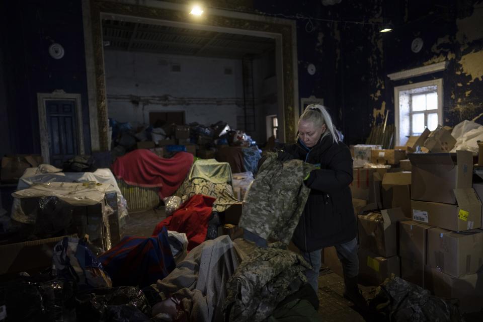 A volunteer folds army clothes inside a Ukrainian volunteer center in Mykolaiv, southern Ukraine, on Monday, March 28, 2022. Ukrainian volunteers have set up a center to supply army and civilians with clothes, food, medicines and makeshift bullet proof vests. (AP Photo/Petros Giannakouris)