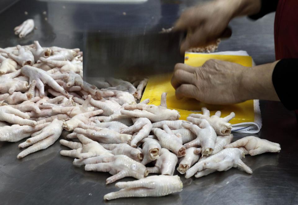 In this Monday, Jan. 23, 2017 photo, chicken feet snacks shop owner Leung Kin-kung chops off nails of chicken feet in Hong Kong. Saturday marks the start of the lunar Year of the Rooster and families in China will reunite for festivities, fireworks and food. While tradition calls for feasting on “auspicious” foods, many will also munch on staple snacks like “phoenix claws,” the Chinese name for chicken feet. (AP Photo/Vincent Yu)