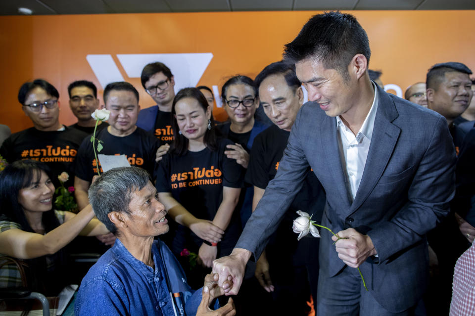 Future Forward Party leader Thanathorn Juangroongruangkit, front right, receives flowers from a supporter in a wheel chair after a Thai court ordered to dissolved his political party in Bangkok, Thailand, Friday, Feb. 21, 2020. Thailand's Constitutional Court on Friday ordered the popular opposition Future Forward Party dissolved, declaring that it violated election law by accepting a loan from its leader. (AP Photo/Gemunu Amarasinghe)