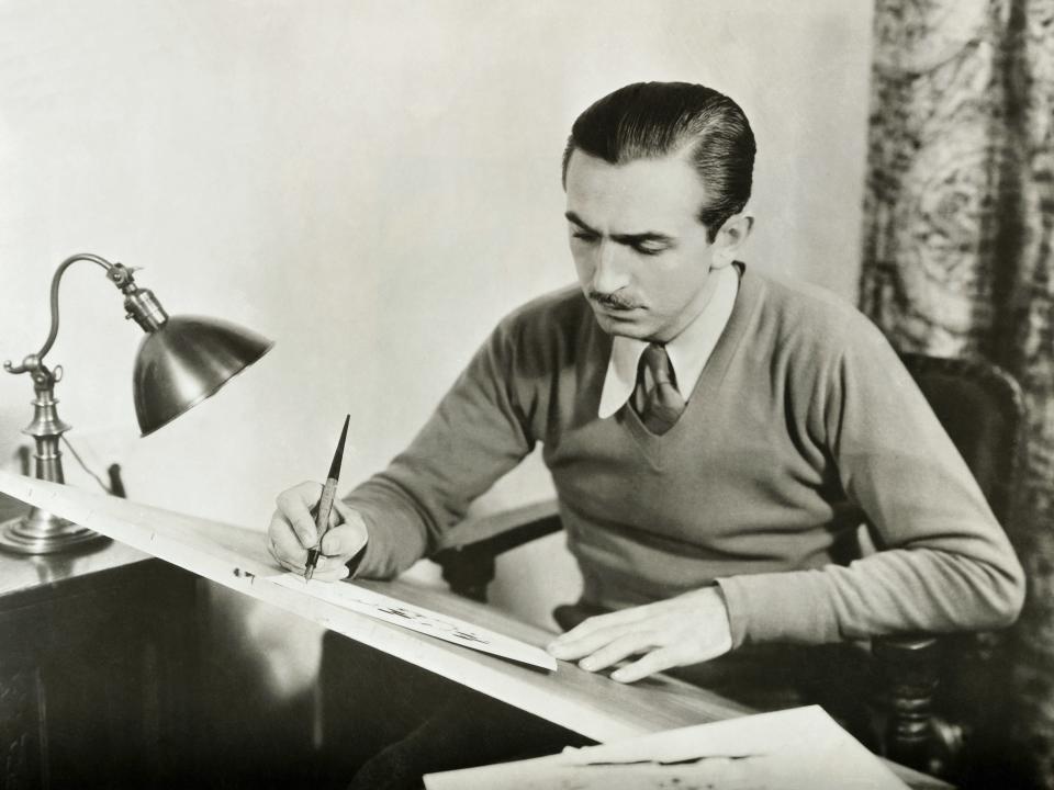 Walt drawing at a slanted desk.