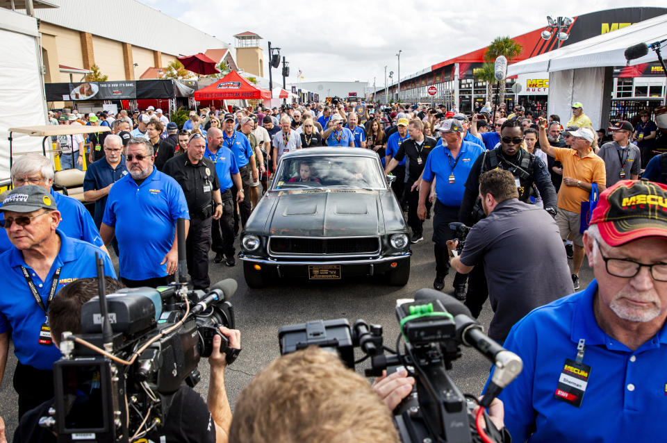 People surround the 1968 "Bullitt" Mustang GT car, Friday, Jan 10, 2020 in Kissimmee, Fla. The iconic Highland Green 1968 Mustang GT that once made history for its appearance in the film “Bullitt” is now making history again. It fetched $3.74 million Friday at Mecum’s Kissimmee auction, making it the most expensive Mustang ever sold. (Patrick Connolly/Orlando Sentinel via AP)