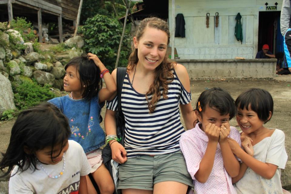 Sarah Frazer pictured in a white and black striped top with four children in a Brazilian village. 