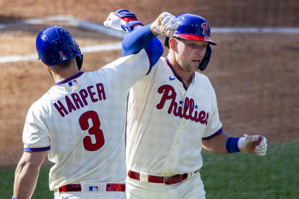 Philadelphia Phillies Rhys Hoskins, right, is congratulated by Bryce Harper (3) after he hit a home run during the first inning of a baseball game, Wednesday, April 7, 2021, in Philadelphia. (AP Photo/Laurence Kesterson)