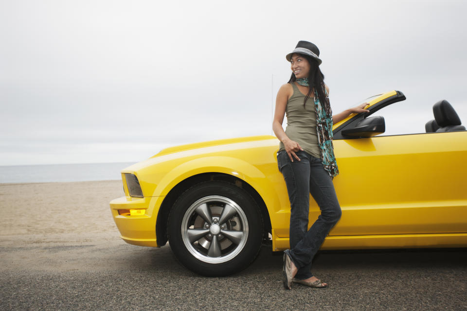 A woman standing next to a yellow convertible