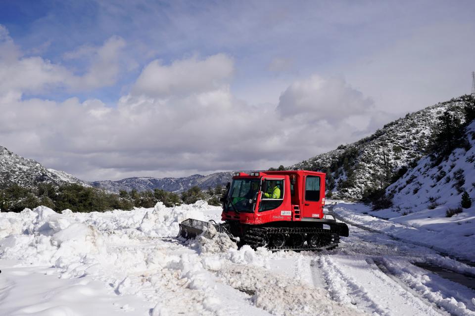 A worker plows snow along State Route 138 near Hesperia, Calif., Wednesday, March 1, 2023. Emergency crews are scrambling to shuttle food and medicine to residents of California mountain communities stranded by back-to-back winter storms.