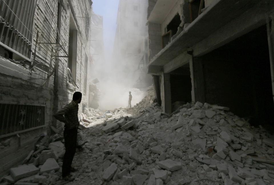 A man stands on the rubble of collapsed buildings at a site hit by what activists said was a barrel bomb dropped by forces loyal to Syria's President Bashar al-Assad on Monday, in the Al-Fardous neighbourhood of Aleppo July 15, 2014. REUTERS/Hosam Katan (SYRIA - Tags: POLITICS CIVIL UNREST CONFLICT)