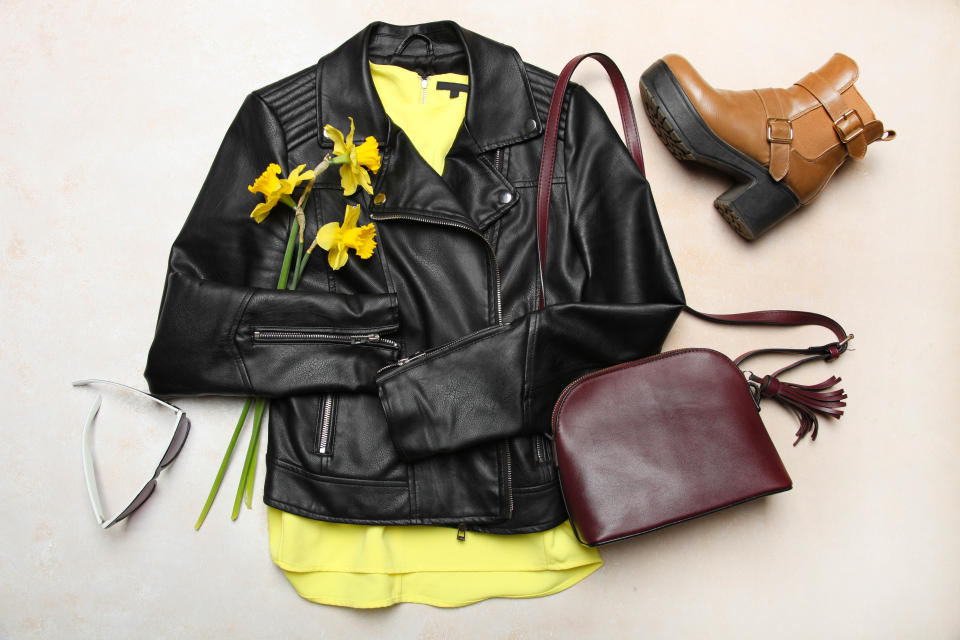 Stylish fashionable black leather jacket, spring boots and small bag on neutral background. Concept outerwear, spring clothes. Top view.