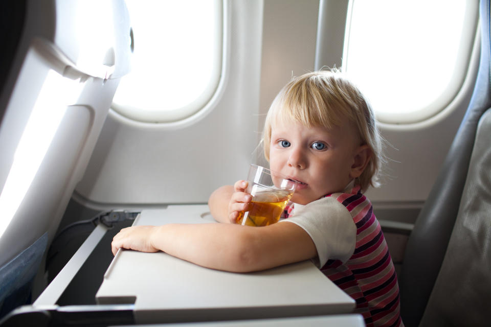 A little girl drinking a drink on a plane
