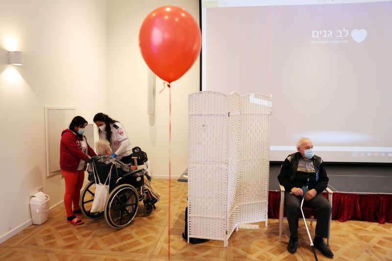 Residents of an assisted living facility receive their booster shot of the vaccination against the coronavirus disease (COVID-19) during a party celebrating the residents receiving their second dose of the vaccine, in Netanya