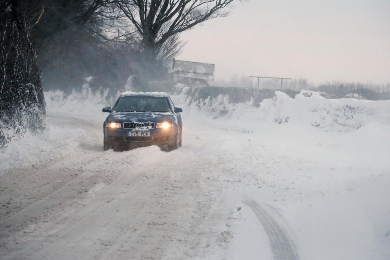 A car is driven along a snow covered road near Okehampton in Devon: PA