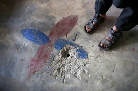 A boy stands next to a crater on the floor of his house, caused by a cluster bomb that according to family looked like a toy and exploded in the hands of a child, in village Jabri, in Neelum Valley