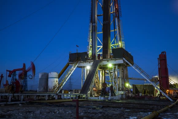 An oil drilling rig with pump jacks in the background.