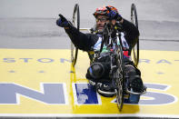 Boston Marathon bombing survivor Marc Fucarile points to spectators while crossing the finish line of the Boston Marathon, Monday, April 17, 2023, in Boston. Fucarile, who lost his right leg in the bombing at the race ten years ago, completed the race as a hand cycle powered athlete. (AP Photo/Charles Krupa)