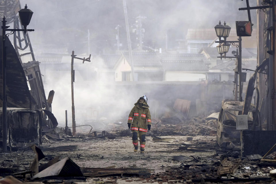 A firefighter walks through the rubble and wreckage of a burned-out marketplace following earthquake in Wajima, Ishikawa prefecture, Japan Tuesday, Jan. 2, 2024. (Kyodo News via AP)