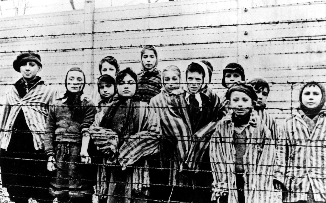 FILE - A picture taken just after the liberation by the Soviet army in January, 1945, shows a group of children wearing concentration camp uniforms at the time behind barbed wire fencing in the Oswiecim (Auschwitz) nazi concentration camp. Germany has agreed to provide more than a half billion euros to aid Holocaust survivors struggling under the burdens of the coronavirus pandemic, the organization that negotiates compensation with the German government said Wednesday. (AP Photo/CAF pap, file) - Anonymous/CAF PAP