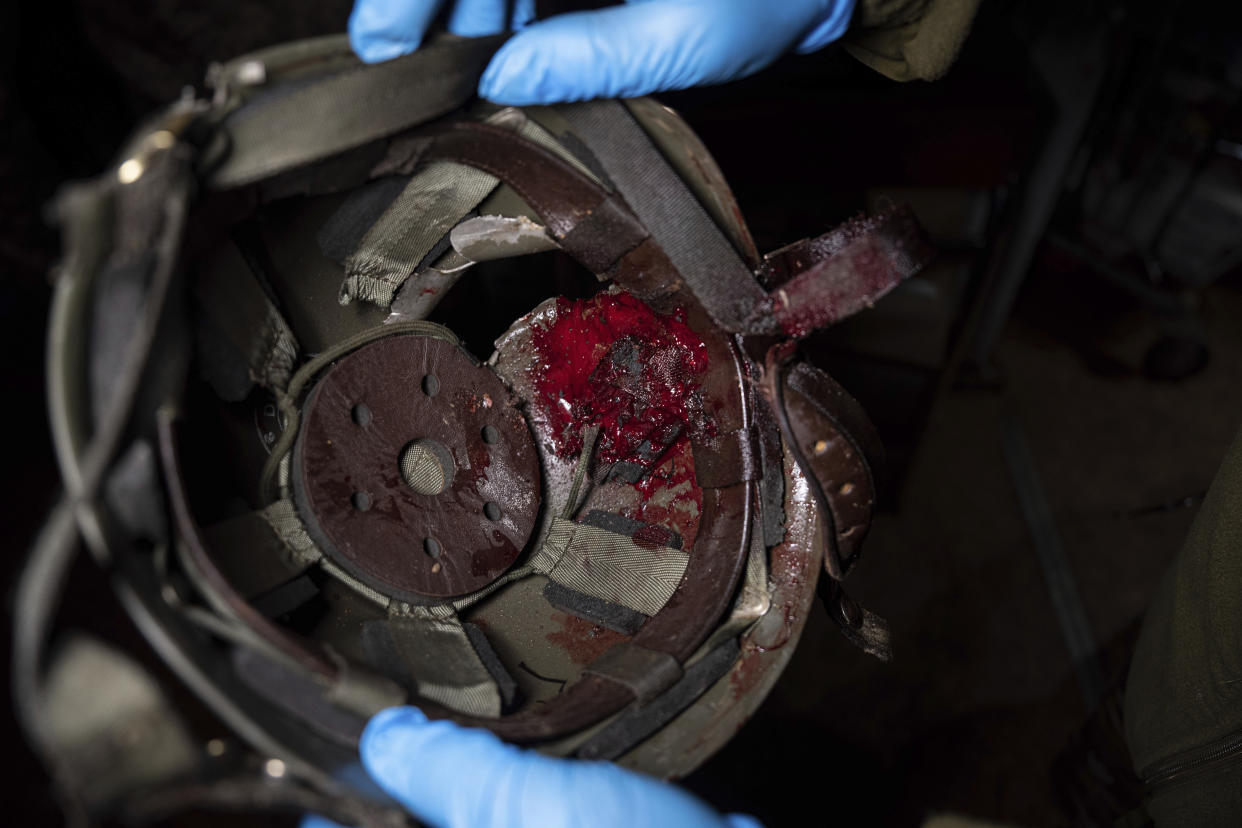 A Ukrainian military medic shows a helmet of an injured serviceman at the hospital in Donetsk region, Ukraine, Monday, Jan. 9, 2023. (AP Photo/Evgeniy Maloletka)