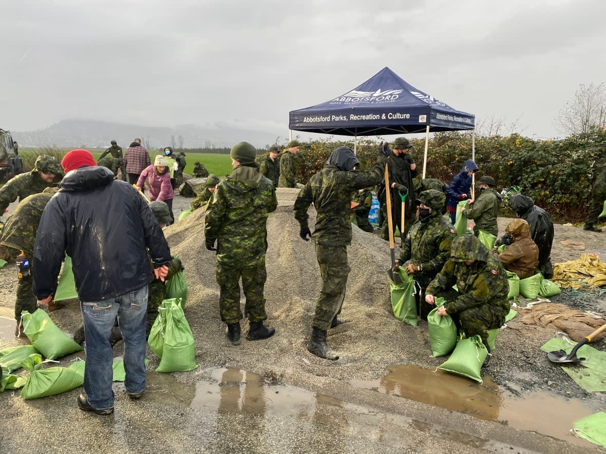 Members of Canada's Armed Forces work with Abbotsford, B.C., residents on Saturday to sandbag an area that was previously flooded when the Nooksack River in Washington state overflowed its banks. (Janella Hamilton/CBC News - image credit)