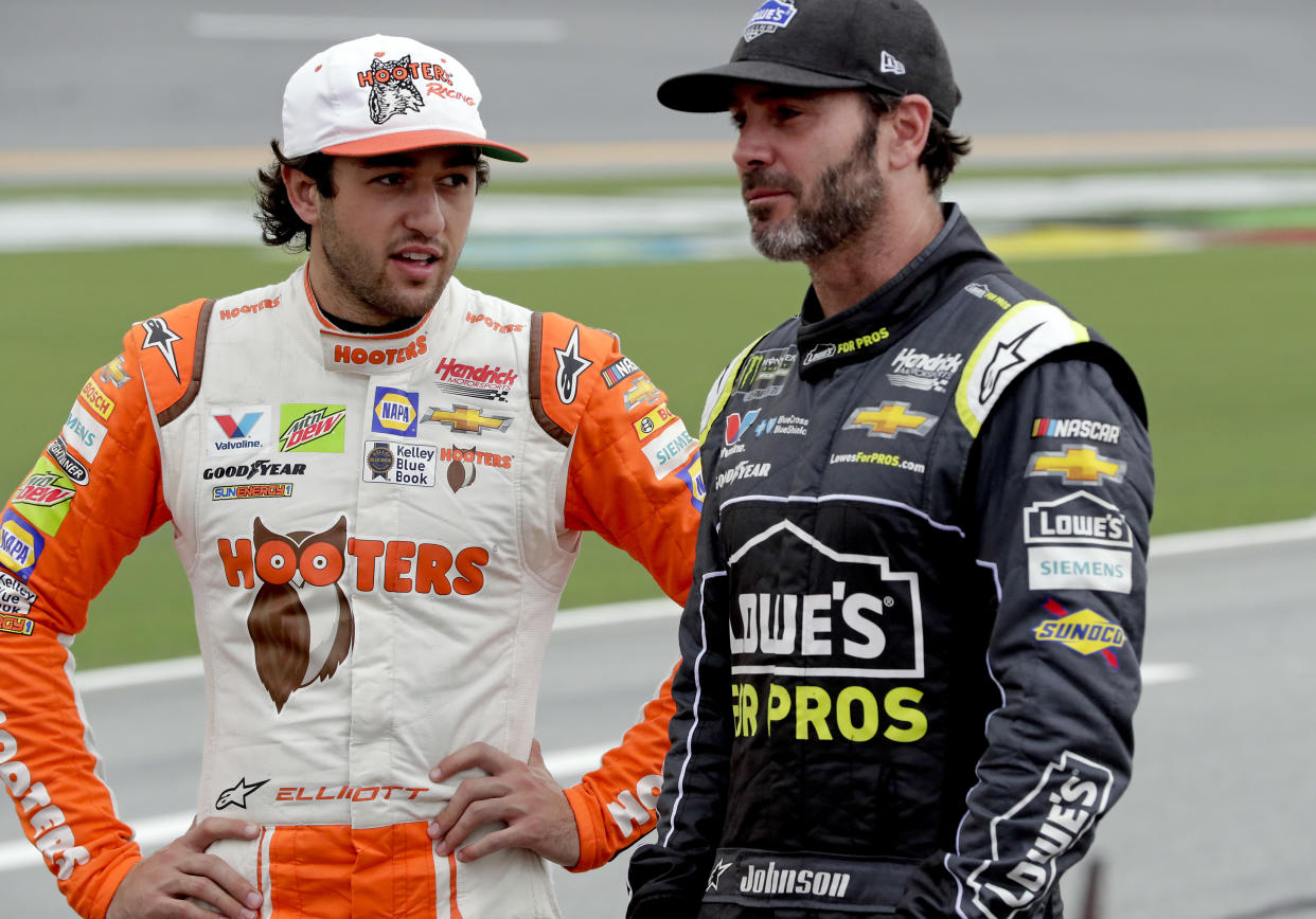 Chase Elliott, left, and Jimmie Johnson talk on pit road during qualifying for the NASCAR Cup Series auto race at Daytona International Speedway, Friday, July 6, 2018, in Daytona Beach, Fla. (AP Photo/John Raoux)