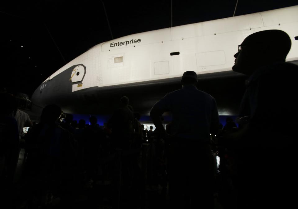 Visitors look at the space shuttle Enterprise in its newly completed pavilion on the deck of the Intrepid Sea, Air & Space Museum in New York, Wednesday, July 10, 2013. With a ribbon-cutting ceremony the pioneering shuttle has been restored from the damages it incurred during Superstorm Sandy. (AP Photo/Seth Wenig)