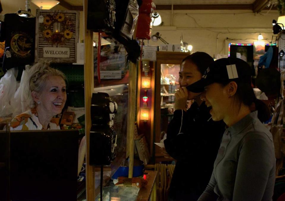 Celee Evans, a la izquierda, vendedora en Mariposa Marketplace, conversa con Hyewon Koo, al centro y Gyeongeun Park, a la derecha, el lunes por la noche. El par de clientes, ambos surcoreanos de 27 años, dijeron que el lunes visitaron el Parque Nacional Yosemite y que también irán a Las Vegas.