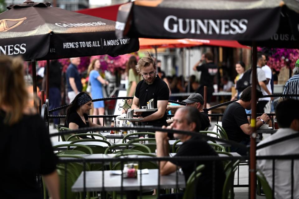 A server works on the patio of a pub in the ByWard Market in Ottawa on June 23, 2023.