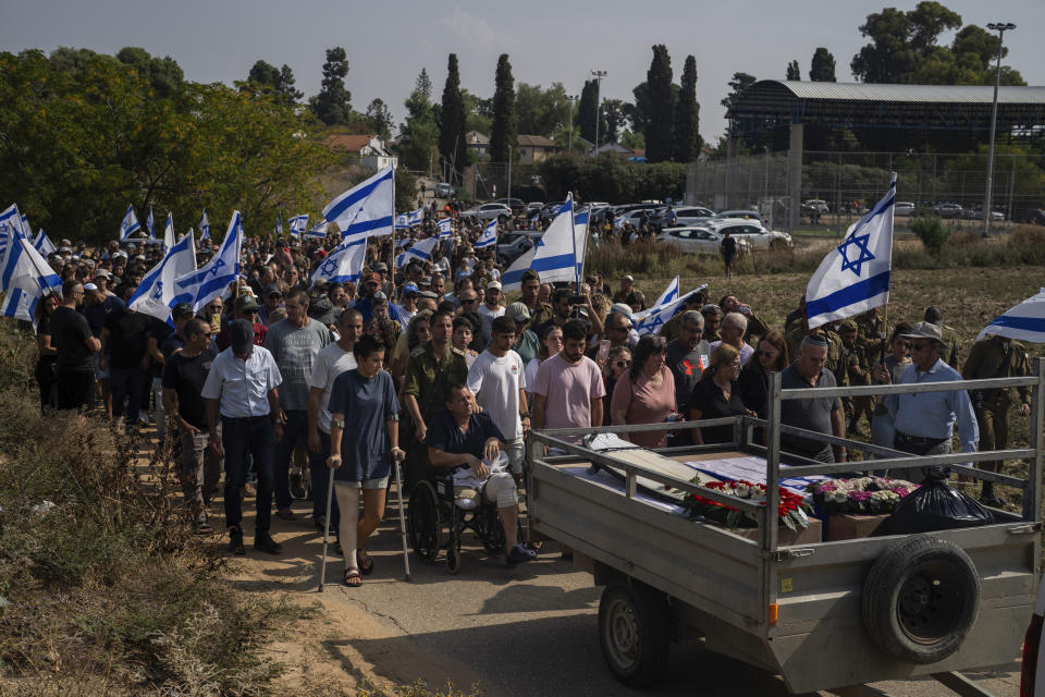 Avida Bachar who came to the funeral on the wheelchair, lost a leg the day of the attacks, attends the funeral with other family members and friends, of his wife Dana and his son Carmel , at Gan Shlomo cemetery, central Israel, Tuesday, Oct. 24, 2023. Carmel Bachar, 15-year-old and his mother Dana lived in kibbutz Be'eri, a small community with a little more than 1,000 people, that was one of more than 20 towns and villages ambushed on Oct. 7 as part of a surprise attack by Hamas militants against Israel where dozens were killed.(AP Photo/Petros Giannakouris)