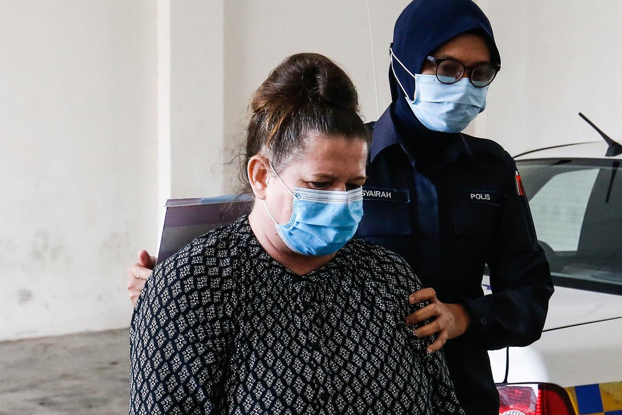 British national Samantha Jones (L), accused of killing her husband in 2018, is escorted by a police officer as she arrives at a court in Alor Setar, in northern Malaysia, on August 3, 2020. - Jones was arrested two years ago after her husband John William Jones was found with a stab wound to his chest in his house on the Malaysian holiday island of Langkawi. (Photo by A. Ammarudin / AFP) (Photo by A. AMMARUDIN/AFP via Getty Images)